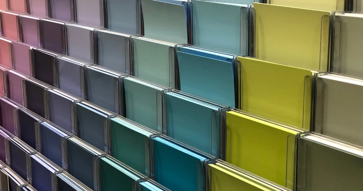 An angled close-up of a paint swatch display rack filled with pink, purple, teal, and chartreuse color chips.