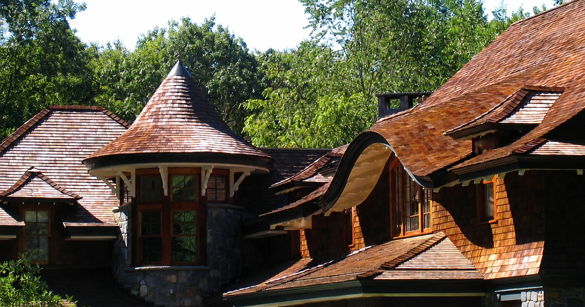 Finished cedar-shingle home with curved rooflines, turret, and surrounding trees in Hastings-on-Hudson, New York.