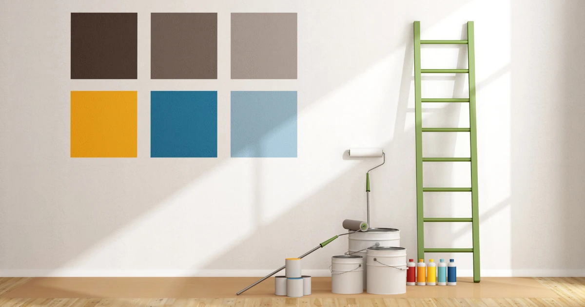 A white wall painted with six square color swatches in brown, taupe, gray, mustard yellow, teal, and light blue, next to paint cans, a roller, and a green ladder.