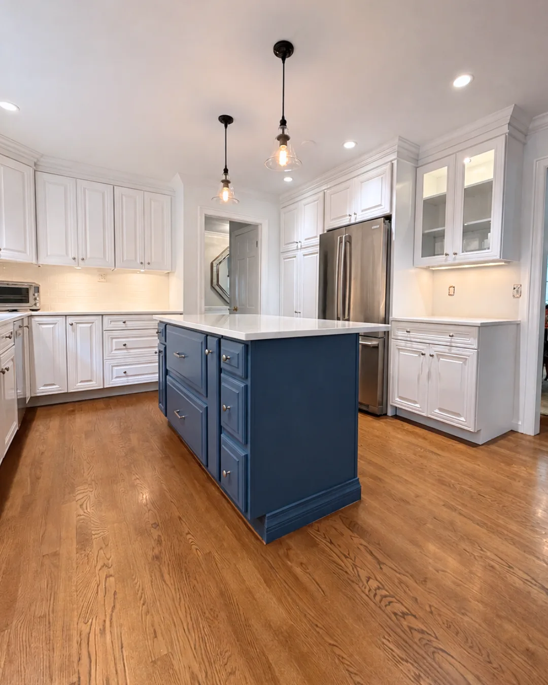 Refinished white kitchen cabinets and a deep blue island in Greenwich.